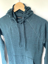 Load image into Gallery viewer, A slate blue-gray heathered pullover hoodie with a gathered drawstring hood, hanging on a wooden hanger against a plain off-white wall.