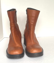 Load image into Gallery viewer, A pair of women's mid-calf boots in smooth brown leather with black soles and side zippers, photographed against a plain white background.