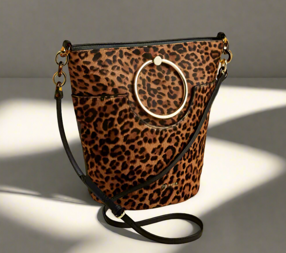 Leopard print handbag with a circular handle on a beige background
