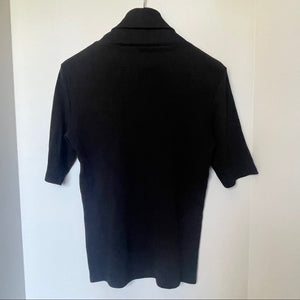 Black short-sleeve shirt on a hanger against a white wall