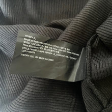 Load image into Gallery viewer, Close-up of a label on a textured gray garment with text details.