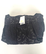 Load image into Gallery viewer, A folded black skirt with a subtle tonal floral jacquard pattern, featuring a white retail hangtag, photographed against a plain white background.