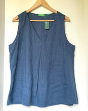 Load image into Gallery viewer, A sleeveless slate blue linen vest hanging on a wooden hanger against a plain off-white wall.