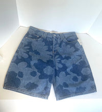 Load image into Gallery viewer, A pair of blue denim shorts with a dark blue floral camouflage pattern, laid flat on a white surface.