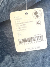 Load image into Gallery viewer, A close-up of a white garment tag attached to blue denim fabric, showing printed product information including size 28, a barcode, and the text '$128.00 USD'.