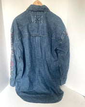 Load image into Gallery viewer, A blue denim shirt jacket with floral embroidery on the sleeves and a Union Jack patch on the back, displayed on a wooden hanger against a white background.