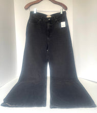 Load image into Gallery viewer, Black wide-leg flare jeans hanging on a wooden hanger against a white background.