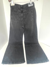 Load image into Gallery viewer, Dark gray washed denim flare jeans hanging on a white hanger against a white background, showing the back pockets and flared legs.