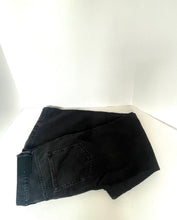 Load image into Gallery viewer, Black denim jeans folded on a white corner studio backdrop, showing the back pocket and waistband area.