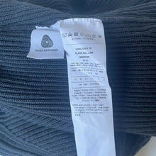 Load image into Gallery viewer, Clothing label on a blue fabric background