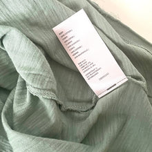 Load image into Gallery viewer, Green fabric with a label on a light background