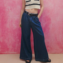 Load image into Gallery viewer, Person wearing blue wide-leg pants and a striped top against a pink background