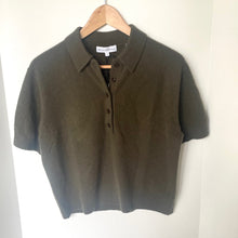 Load image into Gallery viewer, Green polo shirt on a wooden hanger against a white wall
