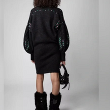 Load image into Gallery viewer, Person wearing a black sweater with decorative elements and black fur boots on a gray background