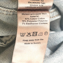 Load image into Gallery viewer, Close-up of a clothing label on fabric with text and symbols.