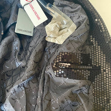 Load image into Gallery viewer, Gray sequined fabric with a Zadig &amp; Voltaire tag and a white flower on a beige background