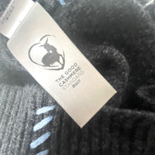 Load image into Gallery viewer, Close-up of a black cashmere sweater with a visible label.