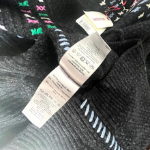 Load image into Gallery viewer, Black sweater with a tag on a textured surface