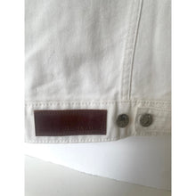 Load image into Gallery viewer, Close-up of a white denim jacket with a brand label on a white background