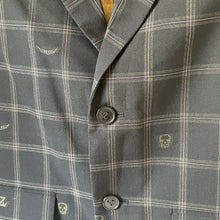 Load image into Gallery viewer, Close-up of a gray plaid jacket with buttons and brand logo.