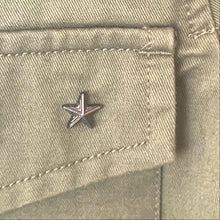 Load image into Gallery viewer, Star-shaped metal pin on a beige fabric background