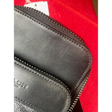 Load image into Gallery viewer, Close-up of a black leather wallet with a zipper on a red background