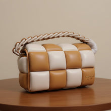 Load image into Gallery viewer, A checkered quilted shoulder bag in tan and cream faux leather, featuring a braided top handle and a gold-tone clasp, shown with its white dust bag and a detached tan strap in the foreground.