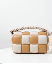 Load image into Gallery viewer, A checkered quilted shoulder bag in tan and cream faux leather, featuring a braided top handle and a gold-tone clasp, shown with its white dust bag and a detached tan strap in the foreground.