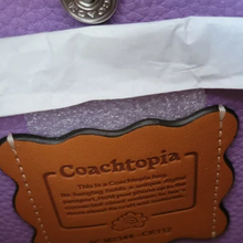 Load image into Gallery viewer, Coachtopia label on a purple surface with a button above it