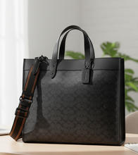 Load image into Gallery viewer, Black quilted handbag with a strap on a white background