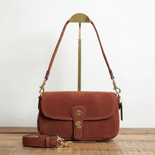 Load image into Gallery viewer, Brown suede handbag with gold accents on a white surface with a plant and vase in the background
