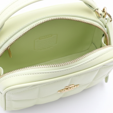 Load image into Gallery viewer, Close-up of a light green handbag with a visible brand label, held by a hand.