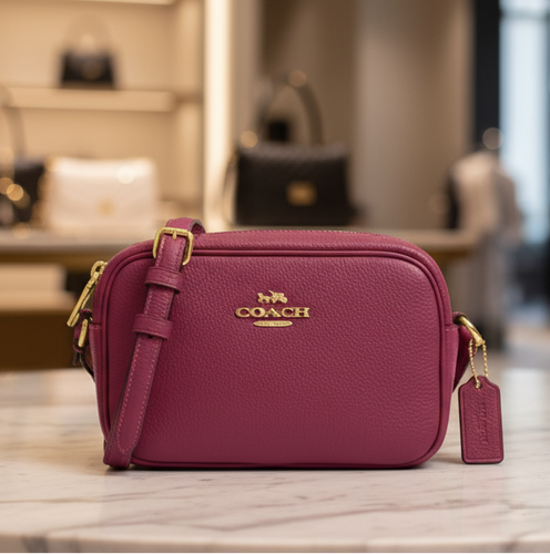 Purple Coach handbag on a marble table with a blurred store interior in the background