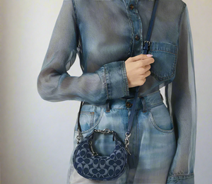 Person wearing a denim outfit with a matching handbag on a white background