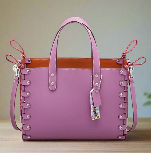 Pink handbag with decorative straps on a white background