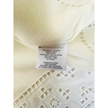 Load image into Gallery viewer, Close-up of a label on a piece of white fabric with intricate patterns.