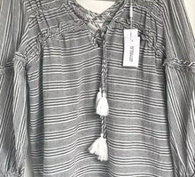 Load image into Gallery viewer, Black and white striped blouse with tassels on a hanger against a white wall
