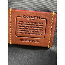 Load image into Gallery viewer, Coach bag with brown leather label on a gray background