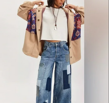 Load image into Gallery viewer, Woman wearing a beige coat with floral sleeves, white top, and patchwork jeans on a white background