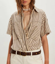 Load image into Gallery viewer, Woman wearing a striped shirt with a deep neckline and white pants on a plain background