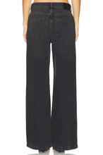 Load image into Gallery viewer, Rear view of a model wearing wide-leg black denim jeans with a faded dark wash, showing the back pockets and waistband.