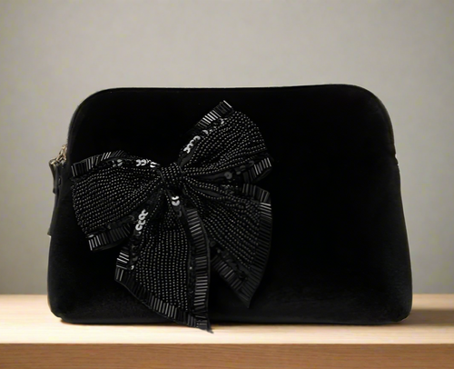 Black clutch bag with a decorative bow on a white background