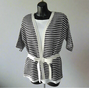 Mannequin wearing a black and white striped outfit with a belt on a plain background