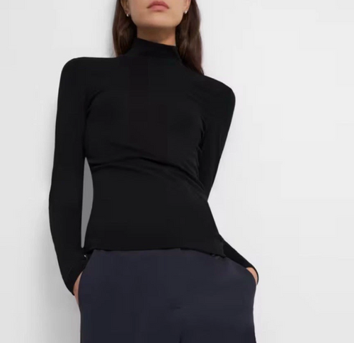 Person wearing a black long-sleeve top against a white background