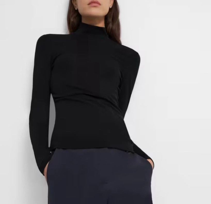 Person wearing a black long-sleeve top against a white background