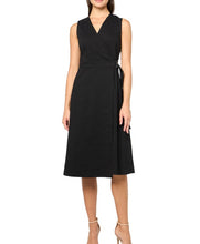 Load image into Gallery viewer, A woman modeling a sleeveless black wrap-style midi dress with a V-neckline and self-tie waist, shown against a plain white studio background.