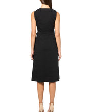 Load image into Gallery viewer, A woman viewed from the back wearing a sleeveless black midi dress with a matching tie belt at the waist, paired with beige high-heeled sandals, against a plain white background.