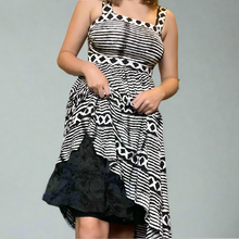 Load image into Gallery viewer, Person wearing a black and white patterned dress in a room with shelves and decor.