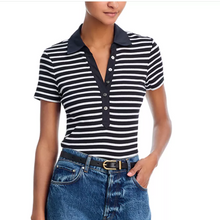 Load image into Gallery viewer, Woman wearing a black and white striped polo shirt with a navy collar and blue jeans.